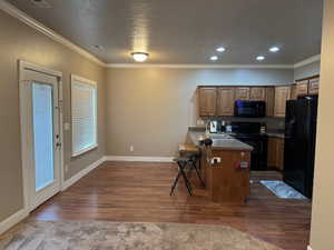 Kitchen featuring black appliances, a kitchen breakfast bar, sink, dark hardwood / wood-style floors, and kitchen peninsula