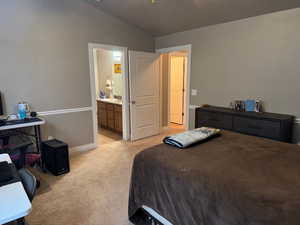 Carpeted bedroom with lofted ceiling and connected bathroom