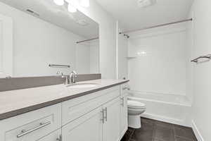 Full bathroom featuring tile patterned floors, vanity, tiled shower / bath combo, and toilet