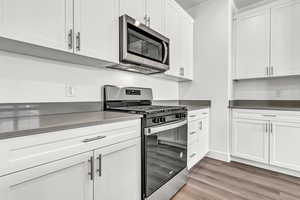 Kitchen with white cabinets, stainless steel appliances, and hardwood / wood-style floors