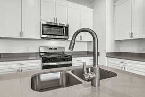 Kitchen featuring stainless steel appliances, white cabinetry, and dark stone countertops