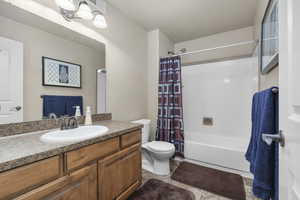 Full bathroom featuring tile patterned flooring, vanity, toilet, and shower / bath combo with shower curtain