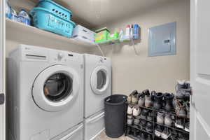 Clothes washing area with tile patterned floors, independent washer and dryer, and electric panel