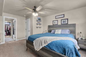 Carpeted bedroom featuring ceiling fan, a walk in closet, and a closet