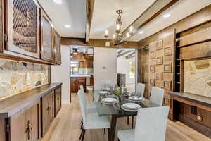 Dining room featuring beam ceiling, ceiling fan with notable chandelier, and light wood-type flooring