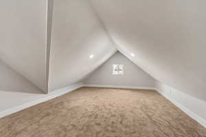 Additional living space with carpet flooring and lofted ceiling