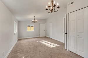 Unfurnished room with a chandelier, carpet, and lofted ceiling