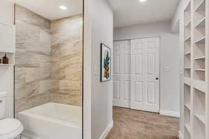 Bathroom featuring tiled shower / bath combo and toilet