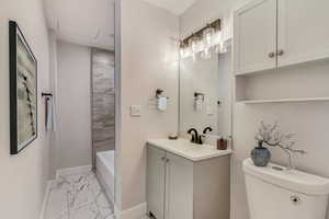 Full bathroom with tiled shower / bath, vanity, and toilet