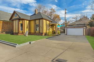 View of front of property with a garage, an outdoor structure, and a front yard