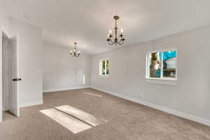 Carpeted empty room with an inviting chandelier