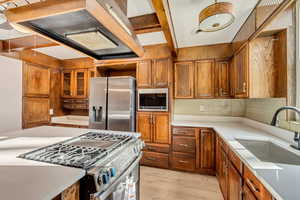 Kitchen featuring premium range hood, sink, light hardwood / wood-style flooring, appliances with stainless steel finishes, and tasteful backsplash