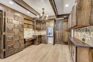 Kitchen featuring pendant lighting, light hardwood / wood-style flooring, decorative backsplash, a notable chandelier, and beam ceiling