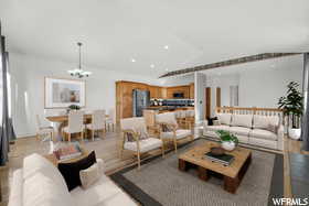 Living room with a notable chandelier, light wood-type flooring, and lofted ceiling