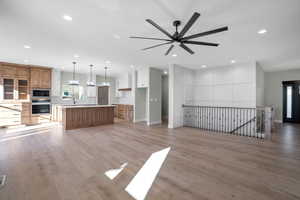 Unfurnished living room with ceiling fan, light hardwood / wood-style floors, and sink