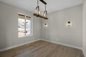 Unfurnished dining area with light hardwood / wood-style flooring and a notable chandelier