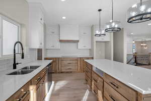 Kitchen featuring dishwasher, white cabinets, sink, light wood-type flooring, and custom range hood