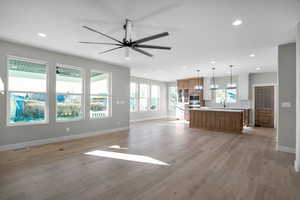 Unfurnished living room with light wood-type flooring, ceiling fan, and sink