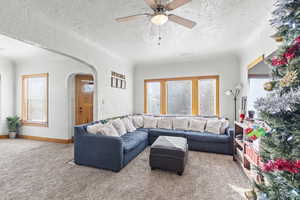 Carpeted living room with ceiling fan, a textured ceiling, and a wealth of natural light