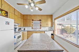 Kitchen with white appliances, tile countertops, plenty of natural light, and sink