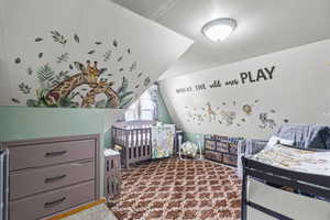 Bedroom with carpet flooring, lofted ceiling, and a crib