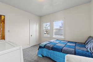 Bedroom featuring light carpet and washer / dryer