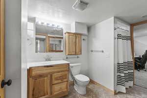 Bathroom featuring tile patterned flooring, vanity, toilet, and a textured ceiling