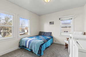 Carpeted bedroom with washer and clothes dryer