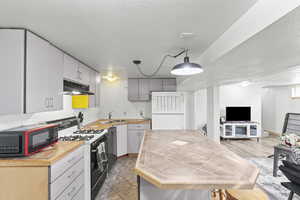 Kitchen featuring gray cabinetry, sink, hanging light fixtures, a textured ceiling, and white appliances