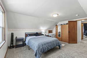 Bedroom with light carpet and vaulted ceiling