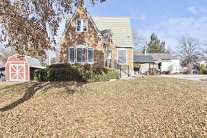 Tudor home with a front lawn and a storage unit