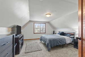 Bedroom with carpet floors and vaulted ceiling