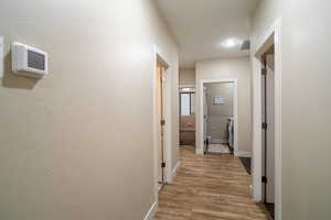 Corridor with light hardwood / wood-style flooring and washer / dryer