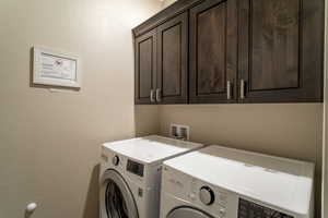 Washroom featuring cabinets and washer and dryer