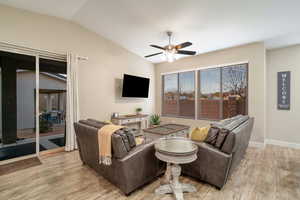 Living room with ceiling fan, light hardwood / wood-style floors, and vaulted ceiling