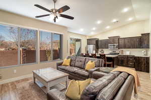 Living room with ceiling fan, light wood-type flooring, and lofted ceiling