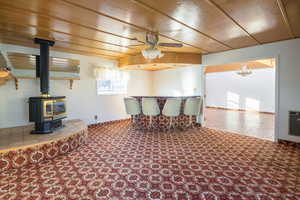 Carpeted living room featuring ceiling fan with notable chandelier and a wood stove