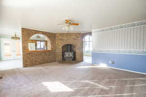 Unfurnished living room with carpet flooring, french doors, a wood stove, and ceiling fan