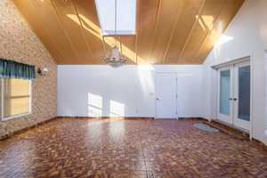 Interior space with a notable chandelier, a healthy amount of sunlight, high vaulted ceiling, and french doors