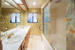 Full bathroom with vanity, toilet, a healthy amount of sunlight, and bath / shower combo with glass door
