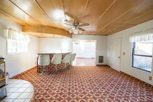 Carpeted dining space with ceiling fan and wood ceiling