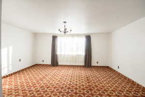 Empty room featuring carpet flooring and a chandelier