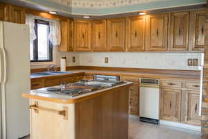 Kitchen with stainless steel gas stovetop, sink, a kitchen island, light hardwood / wood-style floors, and white fridge