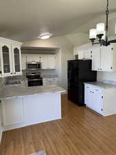 Kitchen with white cabinets, kitchen peninsula, hanging light fixtures, and appliances with stainless steel finishes