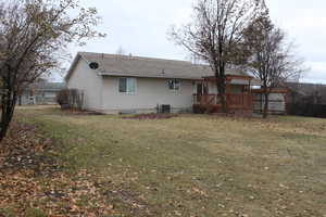 Rear view of property with a wooden deck, a yard, and central AC unit