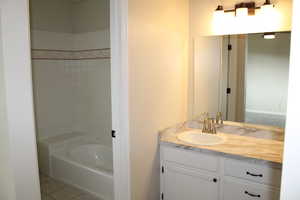 Bathroom with tile patterned flooring, vanity, and a bath