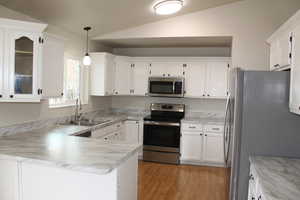 Kitchen with sink, pendant lighting, lofted ceiling, and appliances with stainless steel finishes