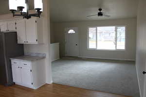 Kitchen featuring white cabinets, ceiling fan with notable chandelier, light hardwood / wood-style flooring, and stainless steel refrigerator