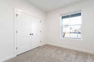 Unfurnished bedroom with light carpet, a closet, and multiple windows