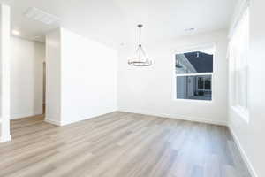 Spare room featuring light hardwood / wood-style flooring and a notable chandelier